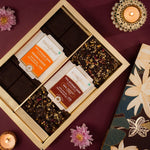 Box of chocolates with floral packaging on a purple surface with candles and flowers.